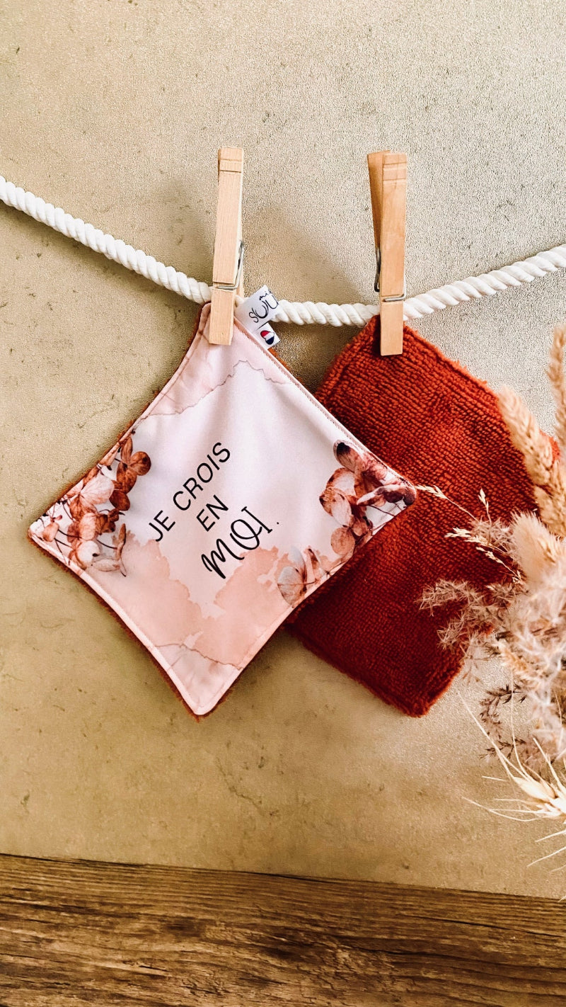 Lingette lavable modèle beige avec le message Je crois en moi, suspendue avec une pince à linge.